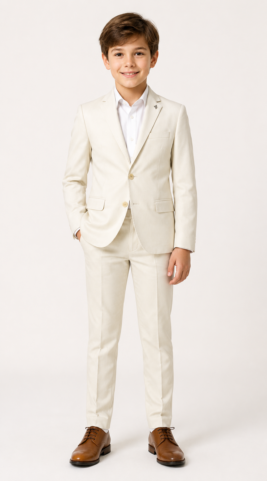 A young boy modeling a light cream/off-white two-piece suit with a white dress shirt and brown leather dress shoes, standing against a plain white studio background.